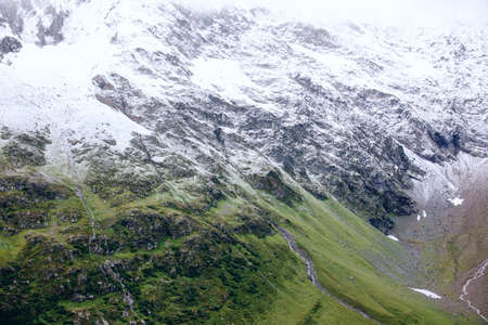 Beautiful view to the mix of green grass and snow.の写真素材