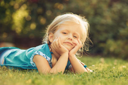 Young blonde girl is enjoying grass in the morning.の写真素材