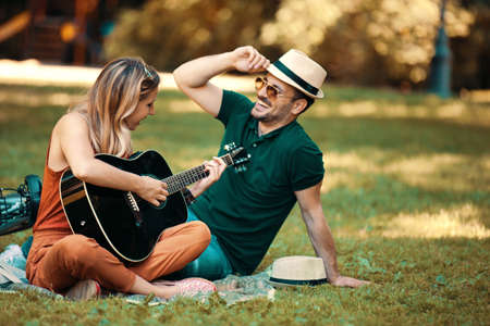 Young couple enjoying park and playing guitar.の写真素材