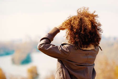 Beautiful woman enjoying autumn day and looking at river.の写真素材