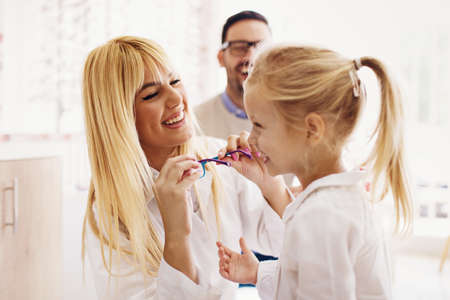 Four year little girl in optics store choosing glasses with her father. Ophtamologist helping.の写真素材