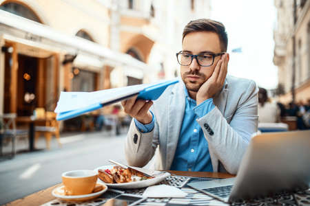 Businessman having breakfast and doing his work in cafe.の写真素材