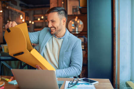 Handsome businessman working in cafe. Using laptop and paperwork. の写真素材