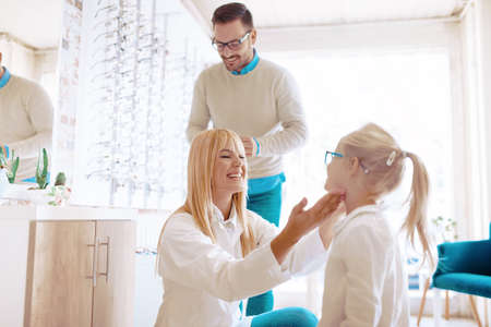 Beautiful four years old girl choosing glasses in optics store.の写真素材