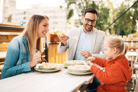 Happy family is enjoying pasta in restaurant.の写真素材