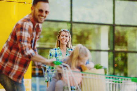 Happy family walking in front of hypermarket after shopping.の写真素材