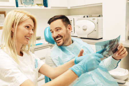 Female dentist and young man patinet in dentist office.の写真素材