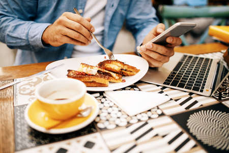 Man having breakfast and doing his work in cafe.の写真素材
