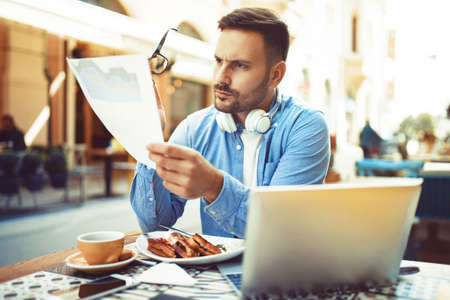 Businessman having breakfast and doing his work in cafe.の写真素材