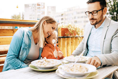 Happy family is enjoying pasta in restaurant.の写真素材