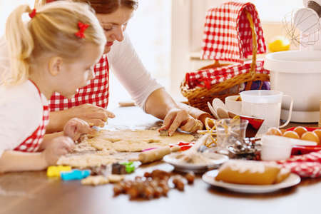 Young mother and her beautiful 4 years old daughter making dough for biscuits. Lifestyle photo. の写真素材