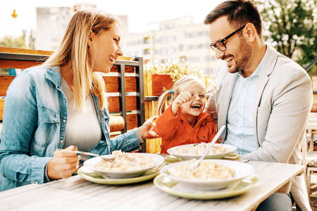 Happy family is enjoying pasta in restaurant.の写真素材
