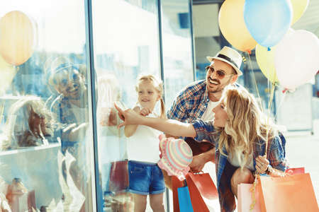 Happy family walking along the shopping mall with shopping bags and balloons.の写真素材