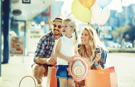 Happy family walking along the shopping mall with shopping bags and balloons.の写真素材