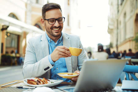 Businessman having breakfast and doing his work in cafe.の写真素材