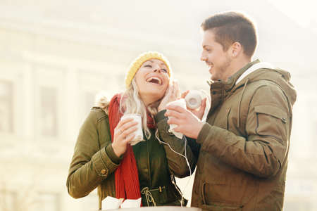 Young couple in love enjoying winter holidays outdoors and having hot drink. の写真素材