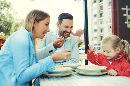 Happy family is enjoying pasta in restaurant.の写真素材