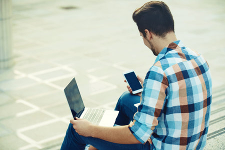 Man is enjoying outside and using gadgets.