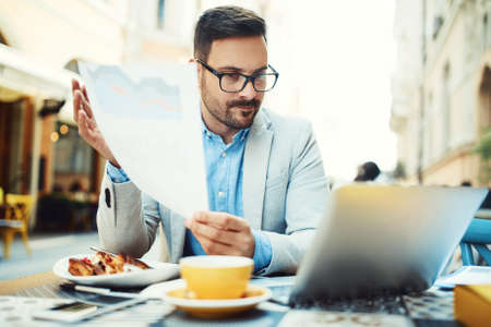 Businessman having breakfast and doing his work in cafe.の写真素材