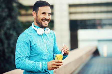 Young athlete man eating fruit after exercising. の写真素材