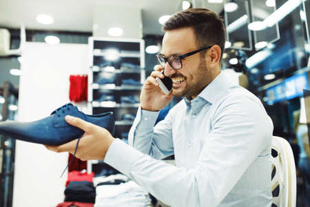 Portrait of handsome young man buying shoes in the store.の写真素材
