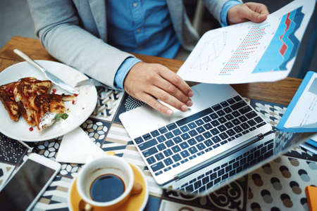 Businessman having breakfast and doing his work in cafe.の写真素材