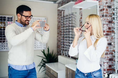 Couple is choosing glasses in optics store. の写真素材