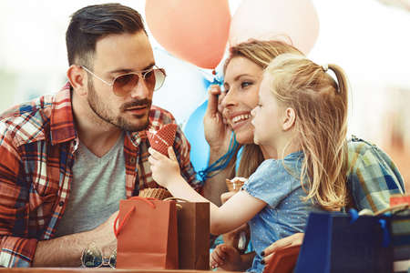 Happy family enjoying ice-cream in cafe after shopping.の写真素材