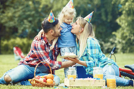 Happy family of three celebrating birthaday party in the park.の写真素材