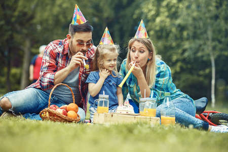 Happy family of three celebrating birthaday party in the park.の写真素材