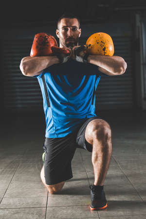 Handsome young man using kettlebell to exercise in garage. の写真素材