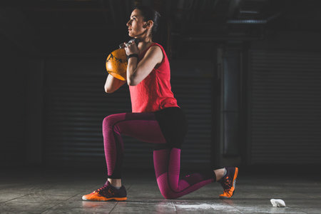 Young strong woman is training with kettlebell.