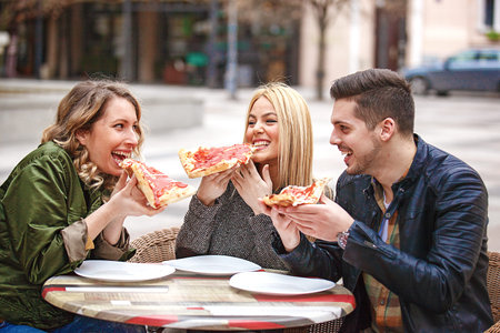 Group of young friends having fun outside and eating pizza.