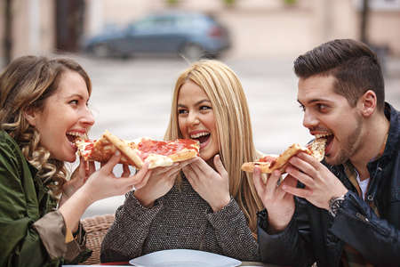 Group of young friends having fun outside and eating pizza.の写真素材