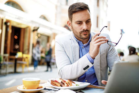 Businessman having breakfast and doing his work in cafe.の写真素材
