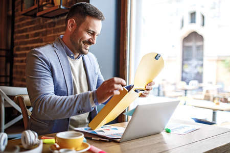 Businessman having breakfast and doing his work in cafe.の写真素材