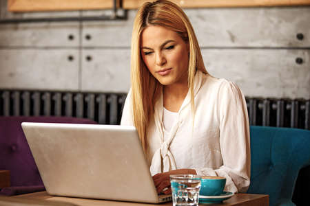 Blonde business woman is enjoying restaurant and fleelance job.の写真素材