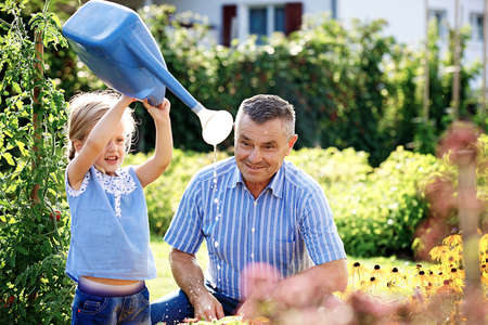 Grandfather is watering flowers with his granddaughter.の写真素材