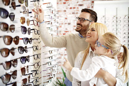 Four year little girl in optics store choosing glasses with her father. Ophtamologist helping. の写真素材