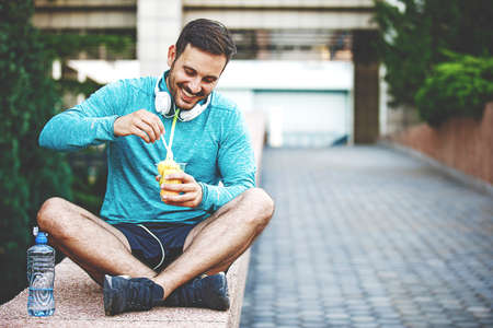 Man is eating fruit salad and relaxing after jogging.の写真素材
