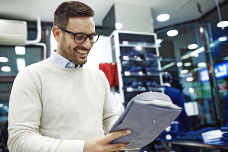 Portrait of handsome young man buying clothes in the store.の写真素材