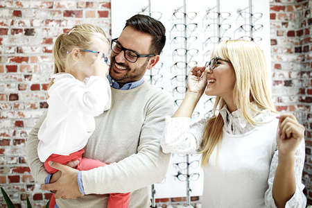 Four year little girl in optics store choosing glasses with her father. Ophtamologist helping. の写真素材