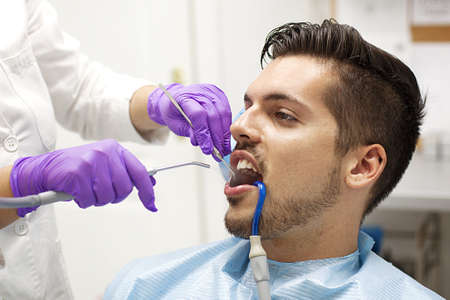 Female dentist and young man patient in dentist office.の写真素材