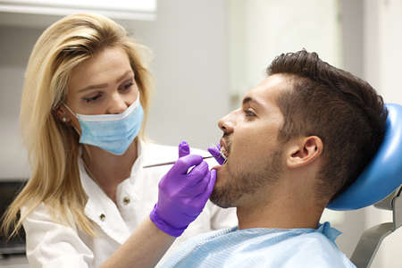 Female dentist and young man patient in dentist office.の写真素材