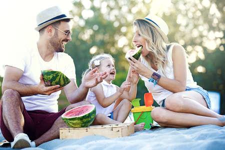Happy family is enjoying beach and eating watermelon.の写真素材