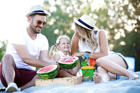 Happy family is enjoying beach and eating watermelon.の写真素材