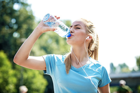 Young fitness woman having break after exercise and drinking water.