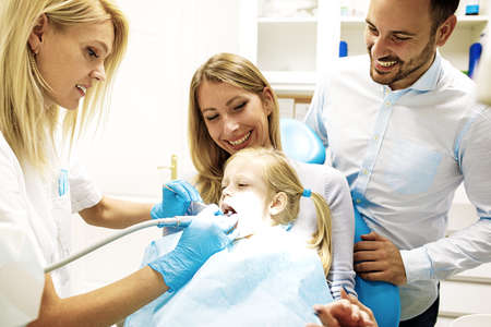 Dentist treating cute blonde child in his surgery. の写真素材