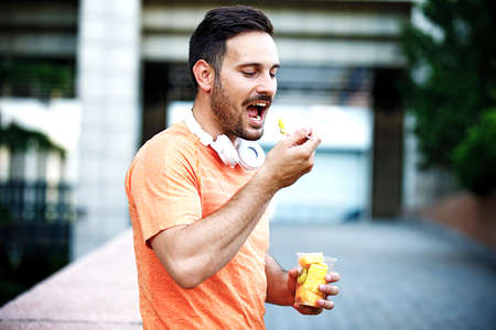 Young handsome man is enjoying fruit salad after jogging.の写真素材