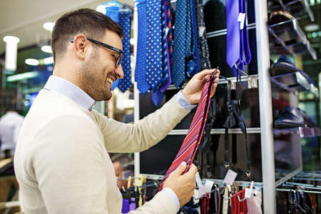 Portrait of handsome young man buying tie in the store.の写真素材